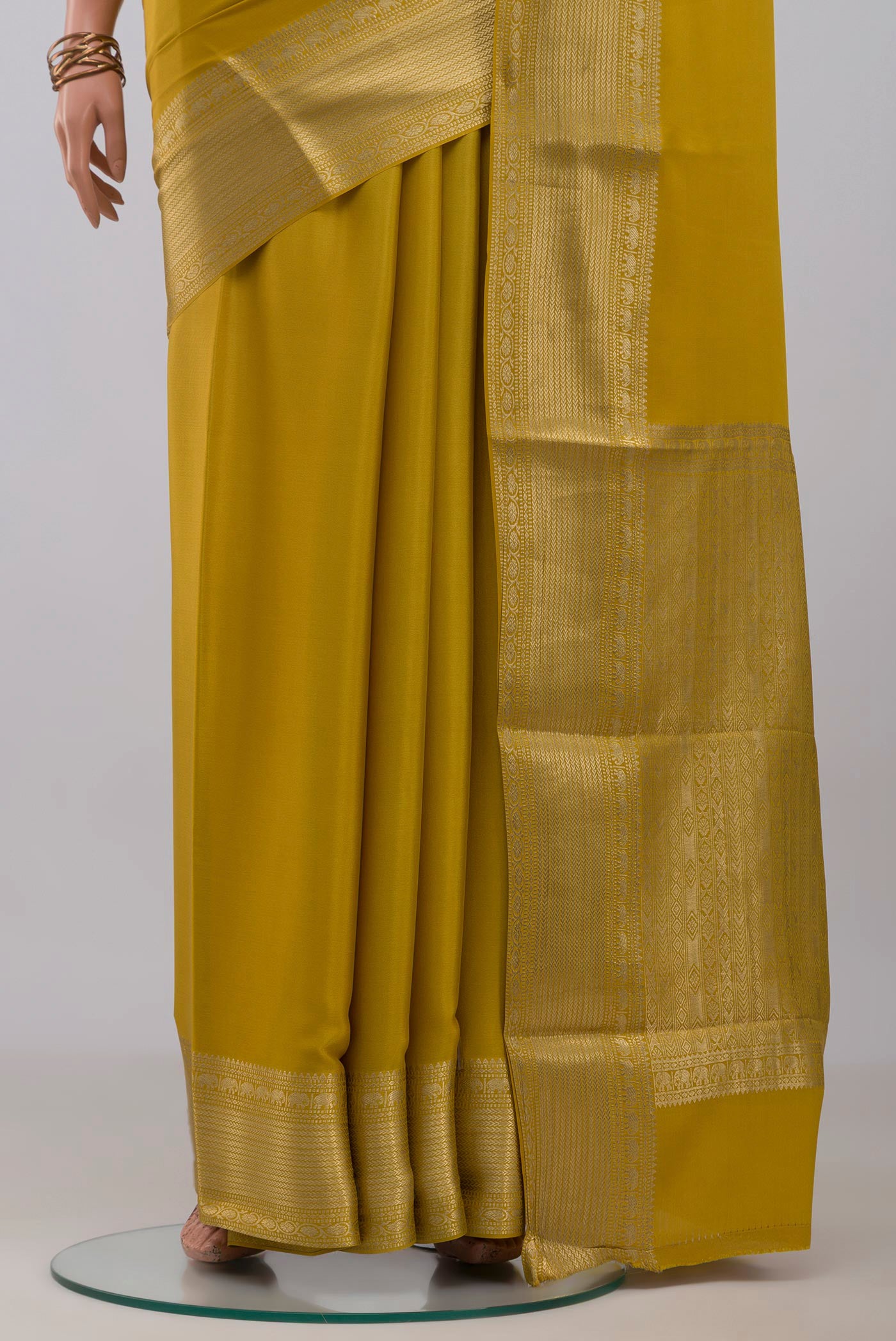 Pleats and pallu of Yellow Mysore Crepe Saree with Plain Body and Zari Border. 