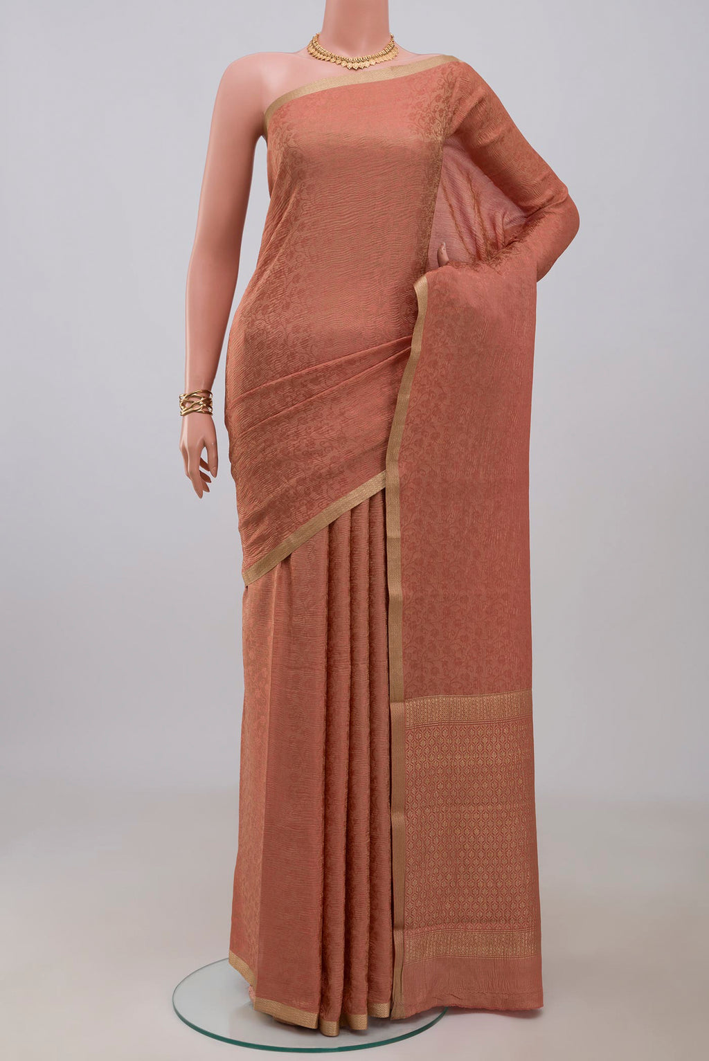 Peach Crepe Saree with Fancy on the body and Zari Border.  displayed on a mannequin