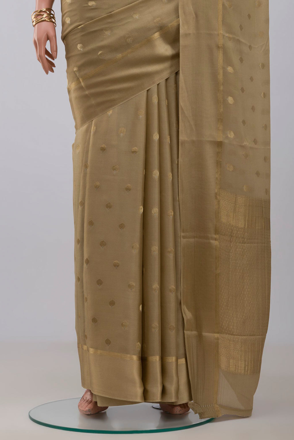 Pleats and pallu of Beige Crepe Saree with Zari Butta on the body and Thin Zari Line. 