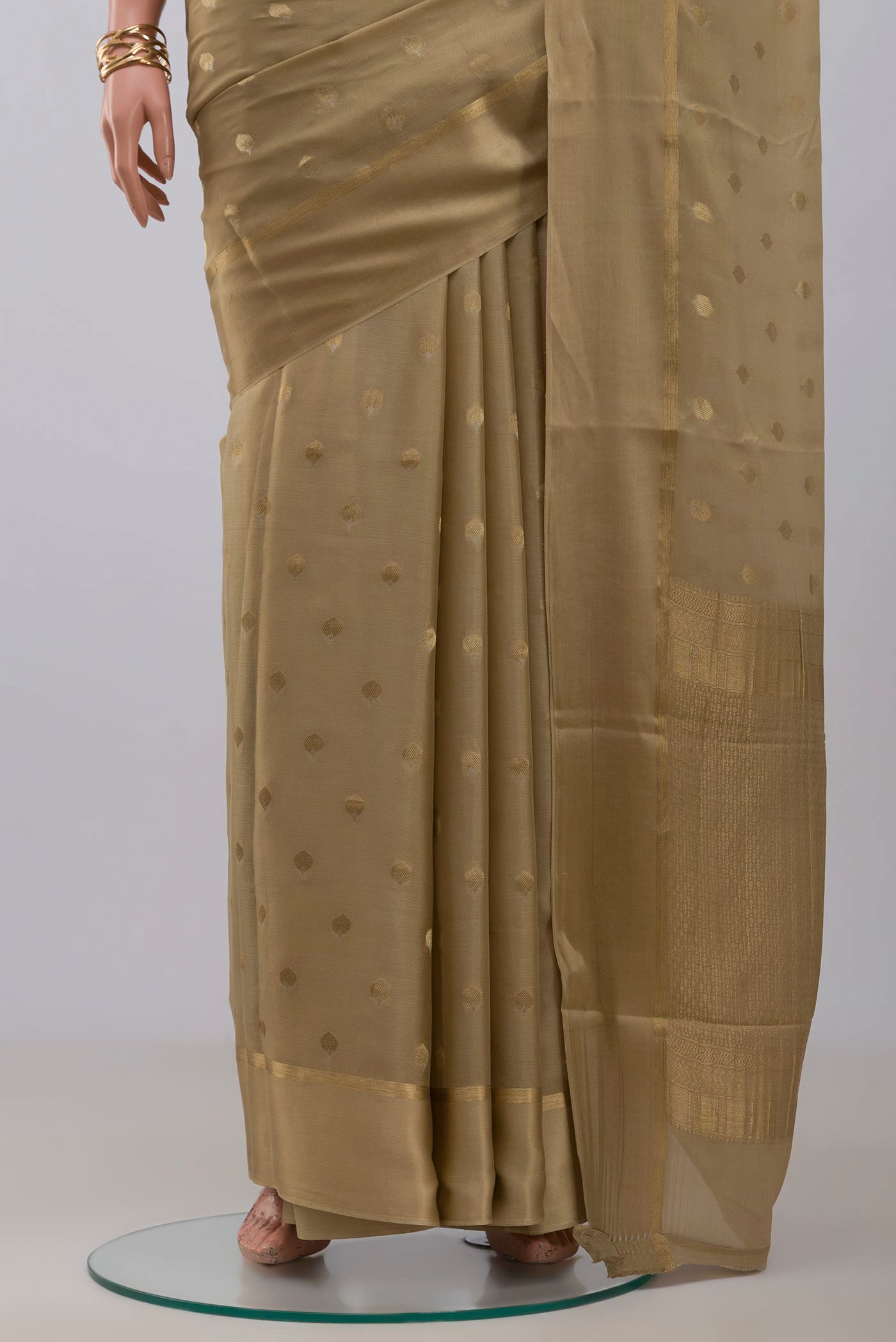 Pleats and pallu of Beige Crepe Saree with Zari Butta on the body and Thin Zari Line. 