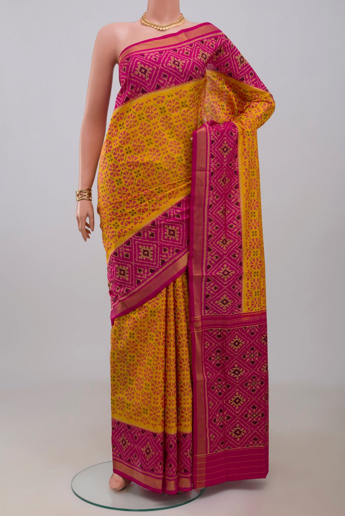 Yellow Rajkot Patola Silk Saree with Ikat design on the body and Ikat Border.  displayed on a mannequin