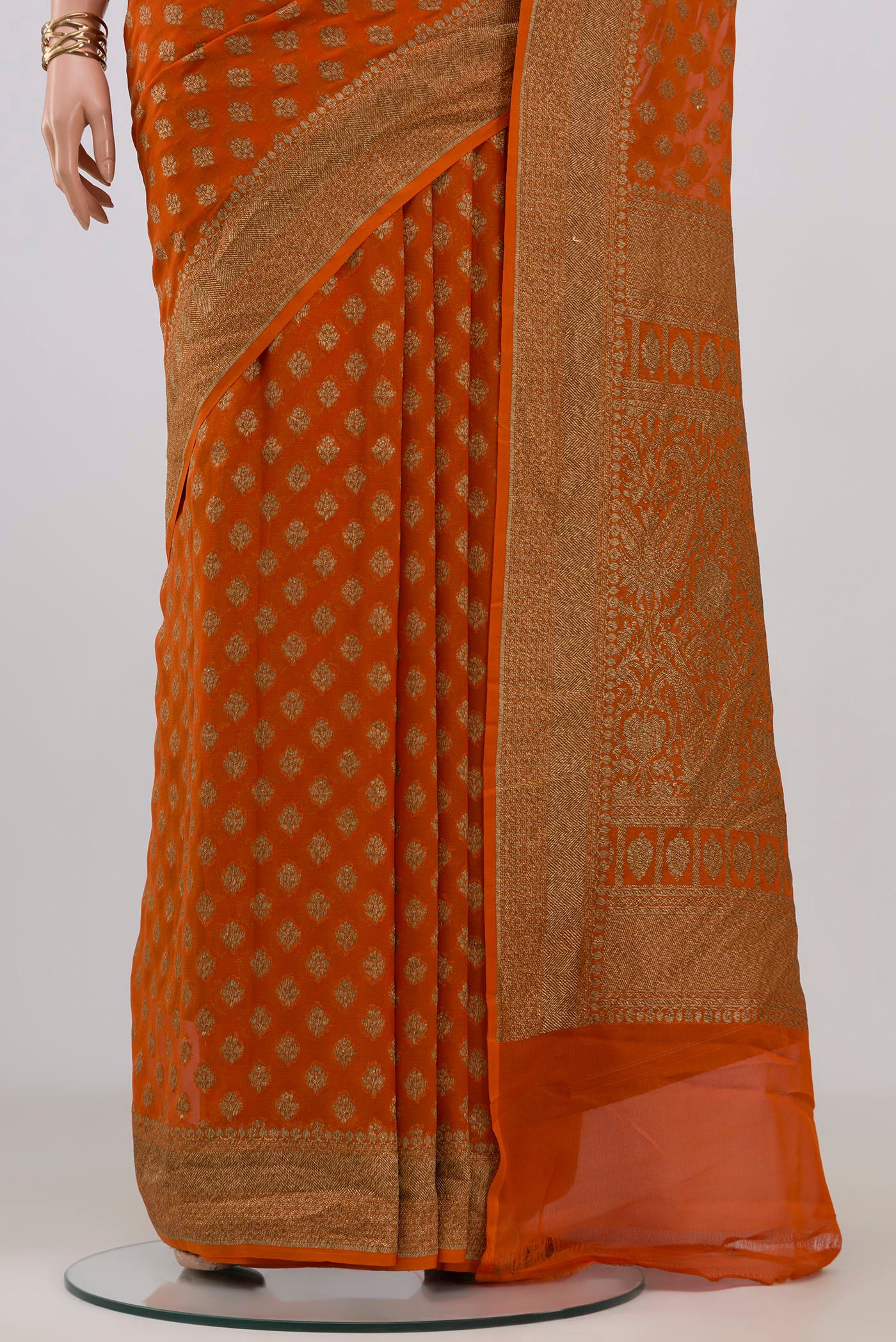 Pleats and pallu of Orange Banarasi Georgette Saree with Zari Butta on the body and Zari Border. 