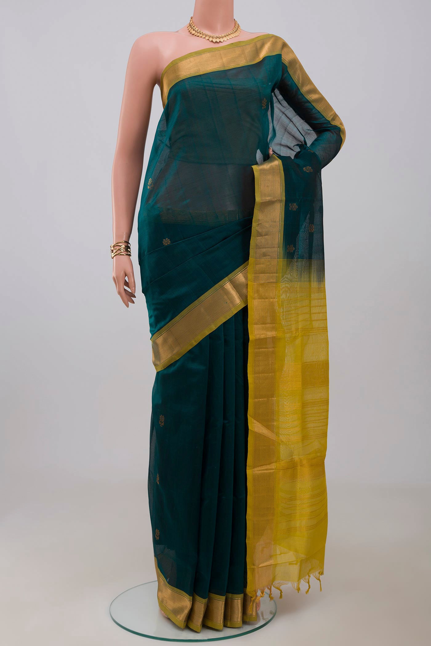 Bottle Green Silk Cotton Saree with Zari Butta on the body and Zari Border.  displayed on a mannequin