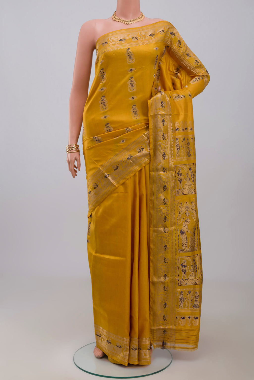 Yellow Baluchari Silk Saree with Zari Butta on the body and Zari Border.  displayed on a mannequin
