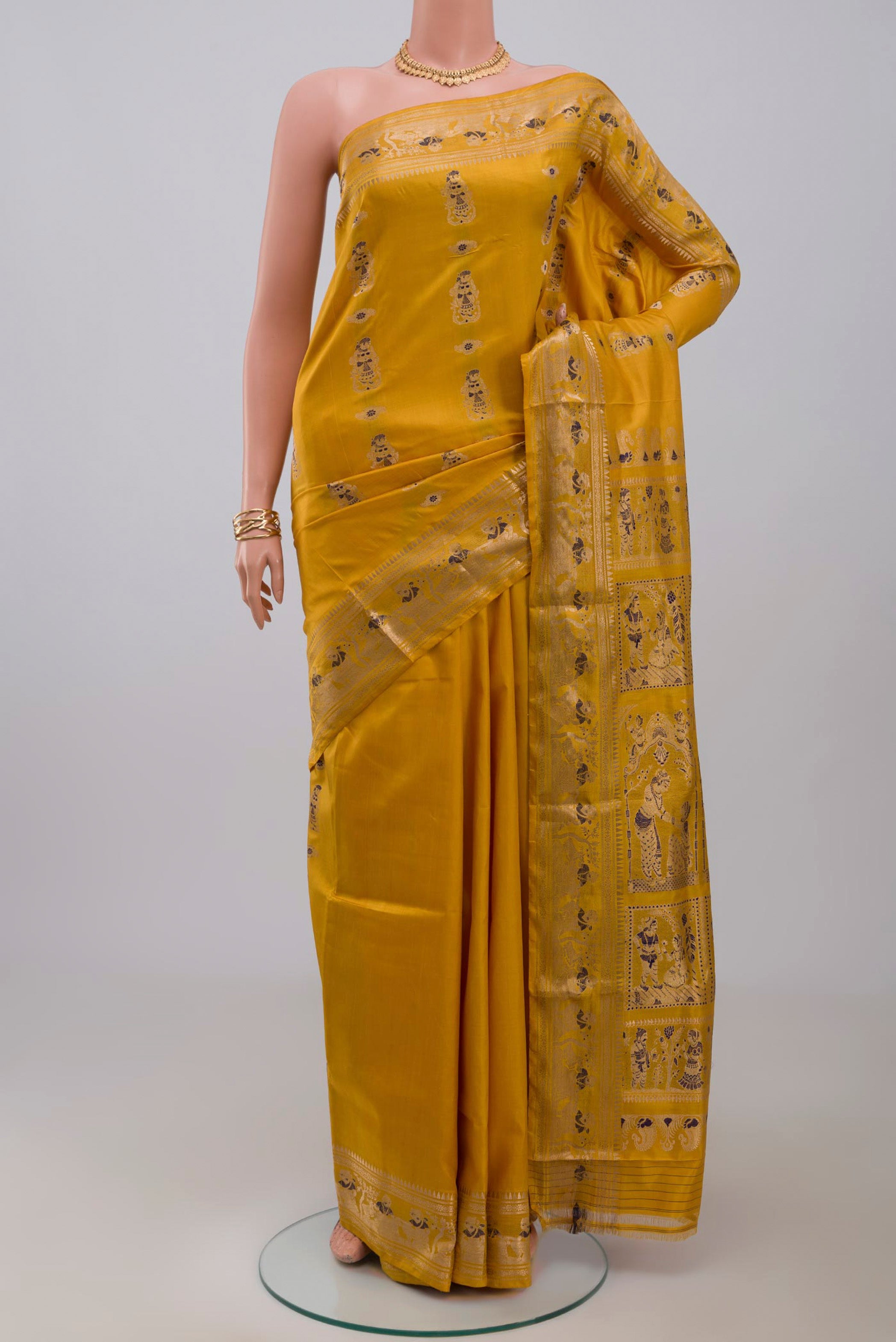 Yellow Baluchari Silk Saree with Zari Butta on the body and Zari Border.  displayed on a mannequin
