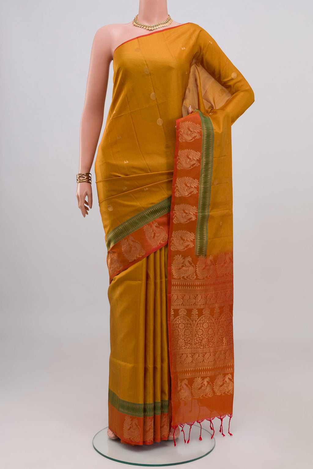 Mustard Soft Silk Saree with Zari Butta on the body and Fancy Border.  displayed on a mannequin