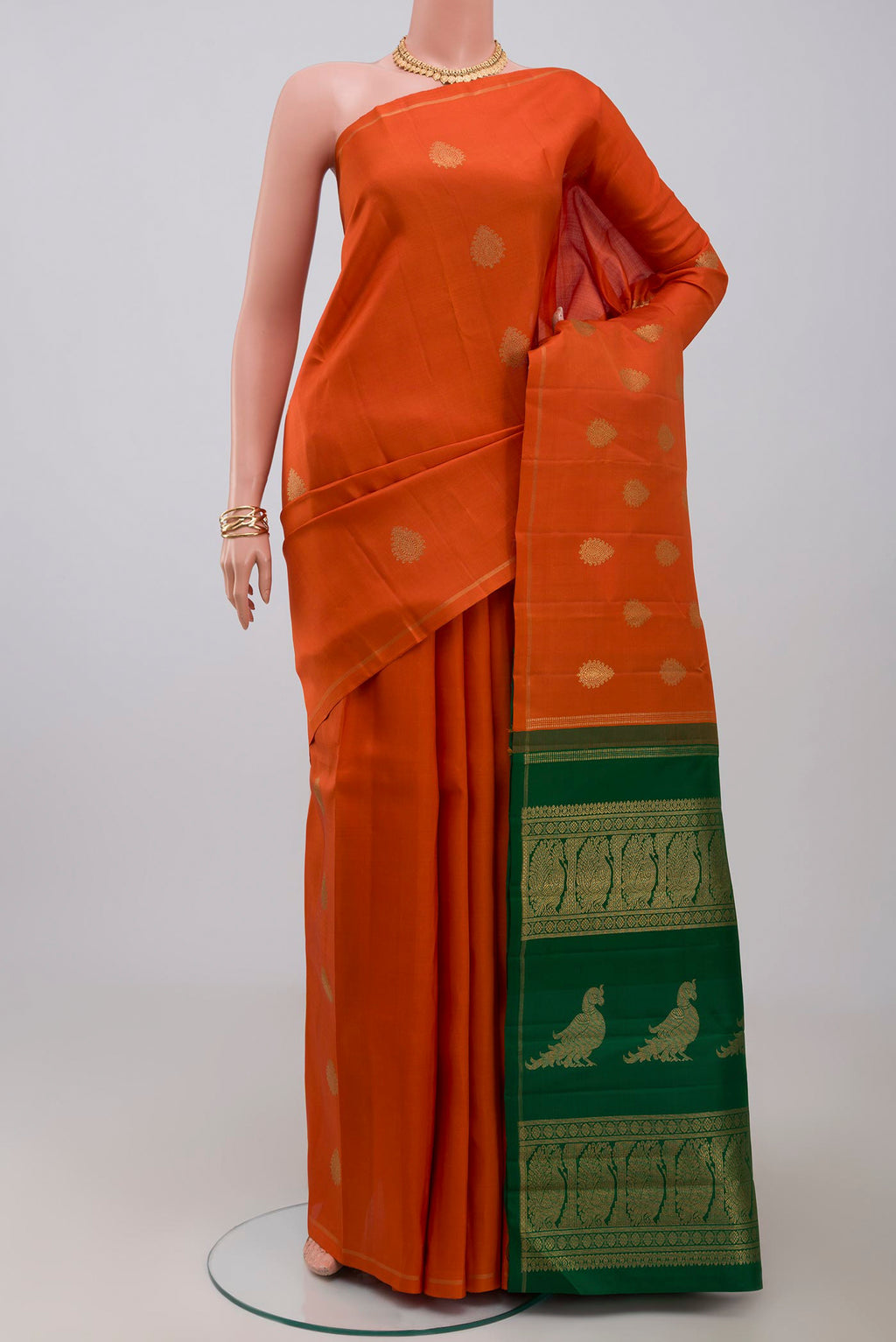 Pure Silk Pure Zari Orange Kanchipuram Saree with Zari Butta on the body and Thin Zari Line.  displayed on a mannequin