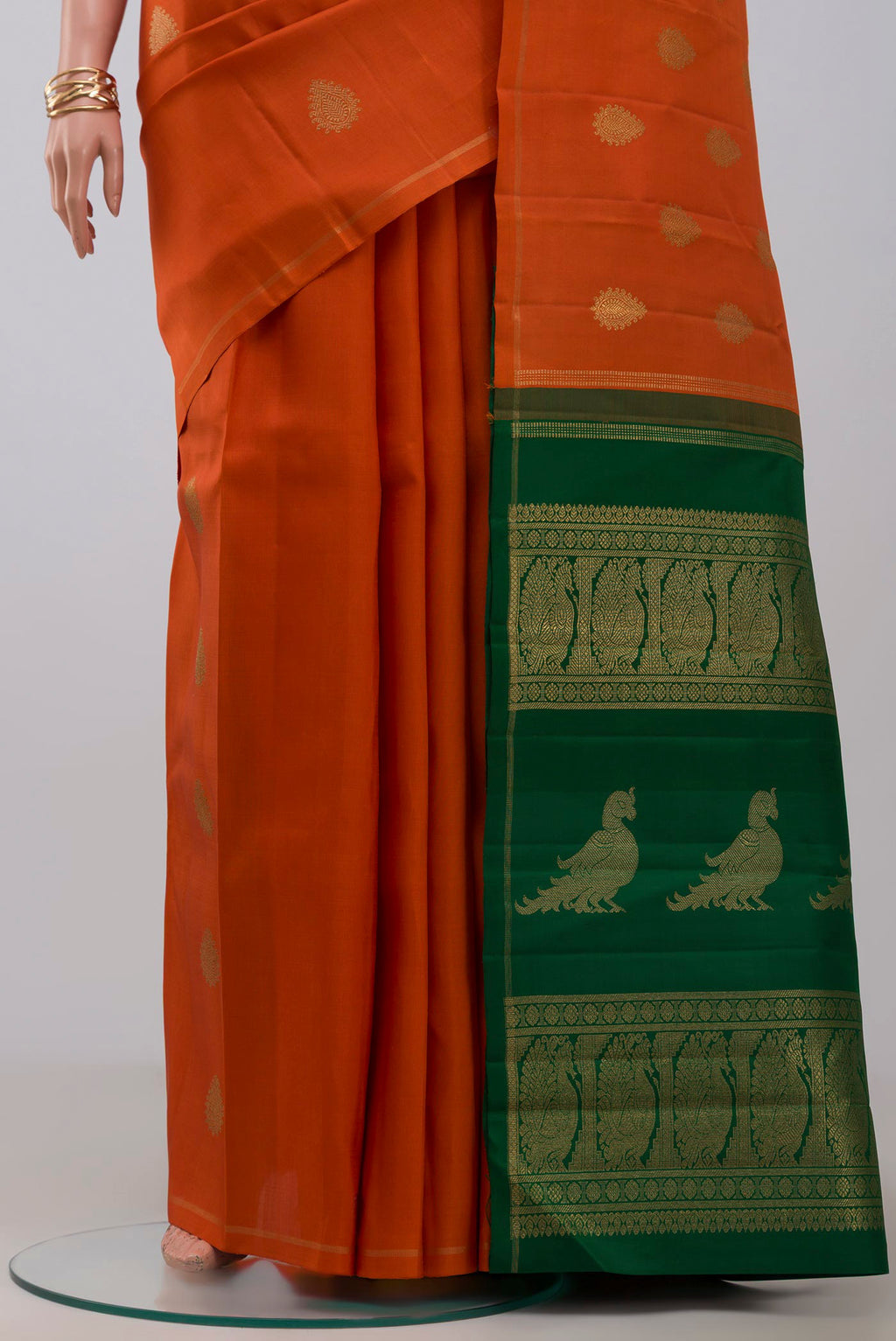Pleats and pallu of Pure Silk Pure Zari Orange Kanchipuram Saree with Zari Butta on the body and Thin Zari Line. 