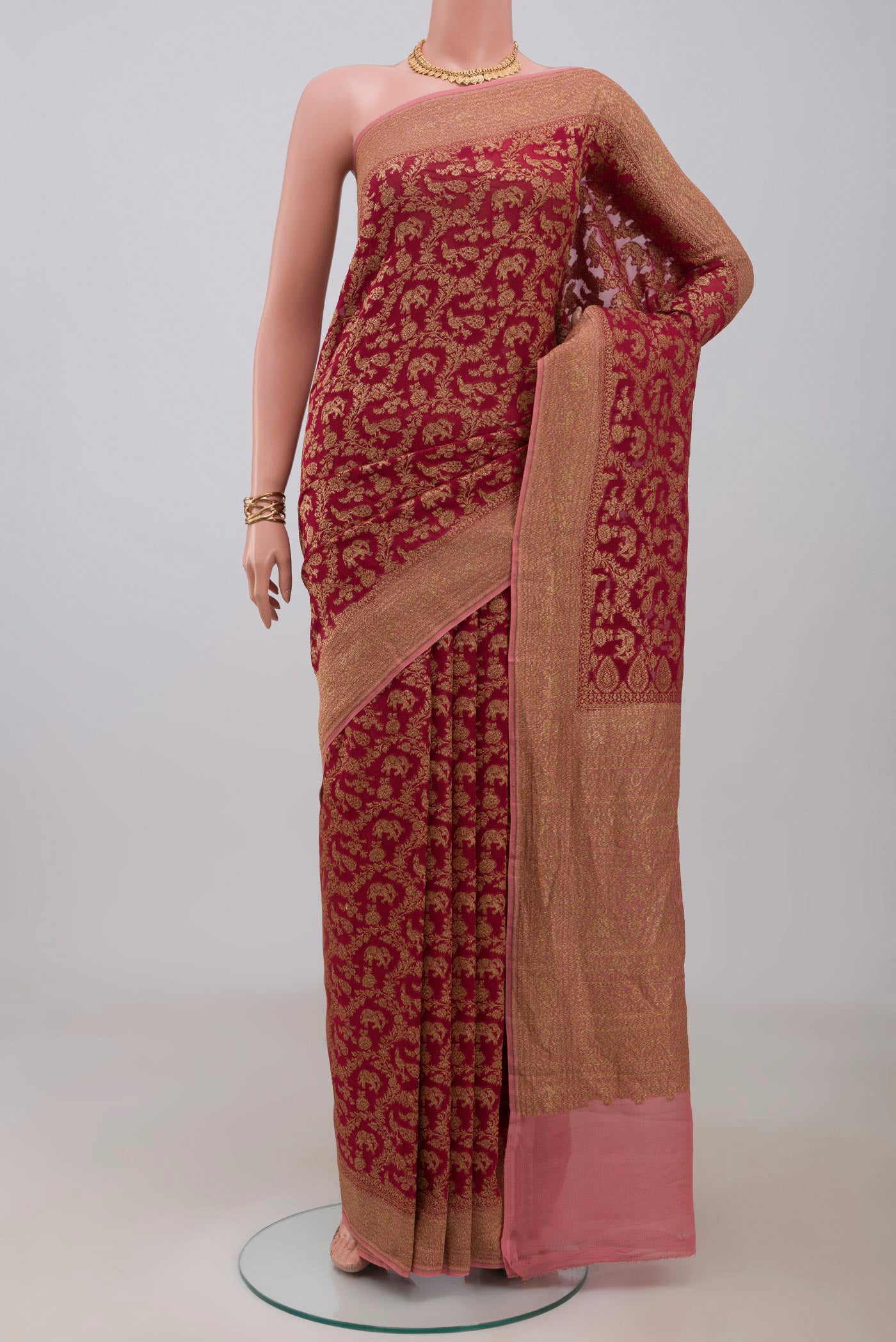 Maroon Banarasi Georgette Saree with Zari Brocade on the body and Zig Zag Border.  displayed on a mannequin