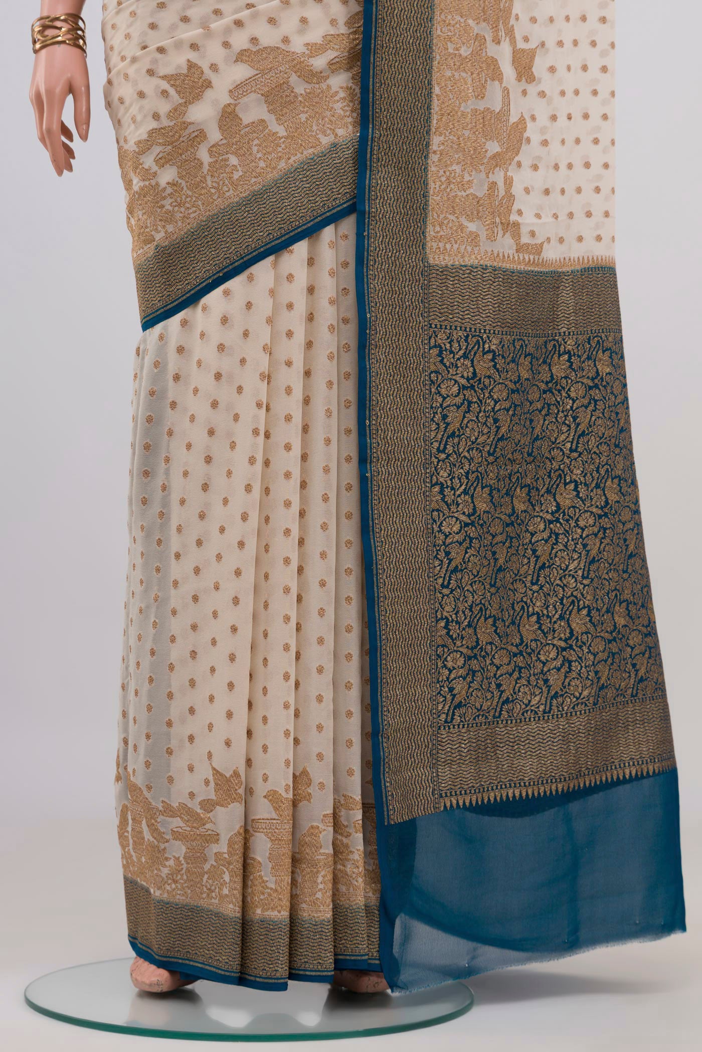 Pleats and pallu of Cream Banarasi Georgette Saree with Zari Butta on the body and Zari Border. 