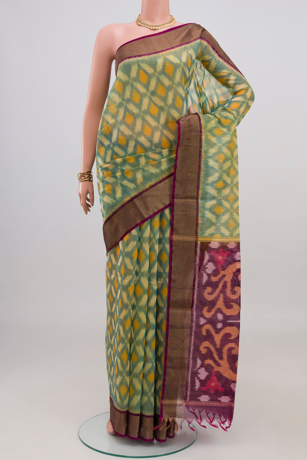 Green Silk Cotton Saree with Ikat design on the body and Zari Border.  displayed on a mannequin