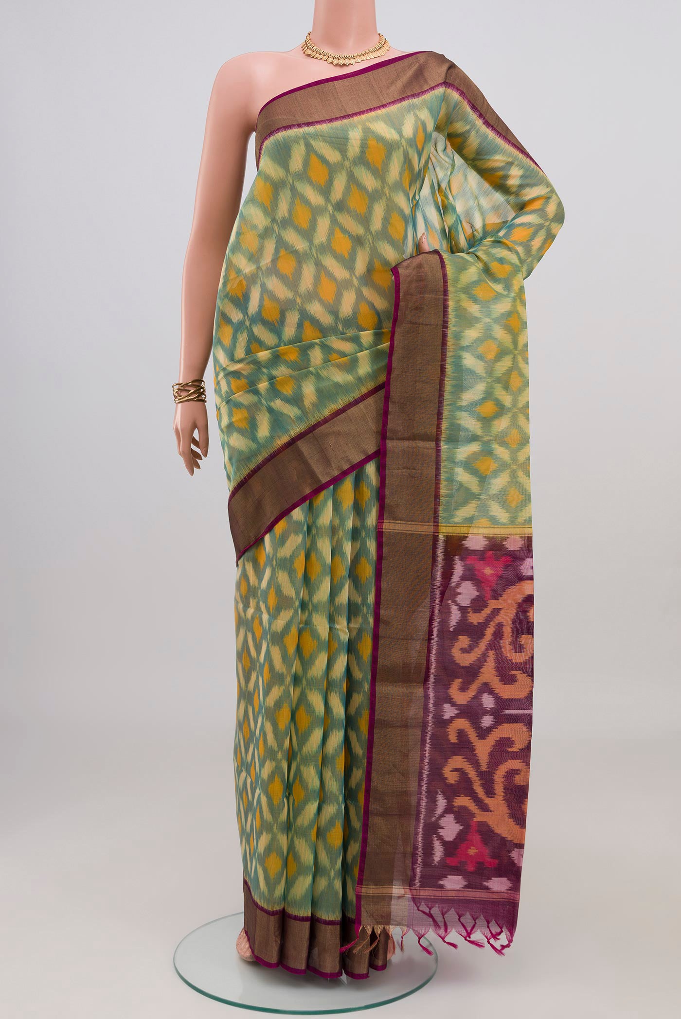 Green Silk Cotton Saree with Ikat design on the body and Zari Border.  displayed on a mannequin