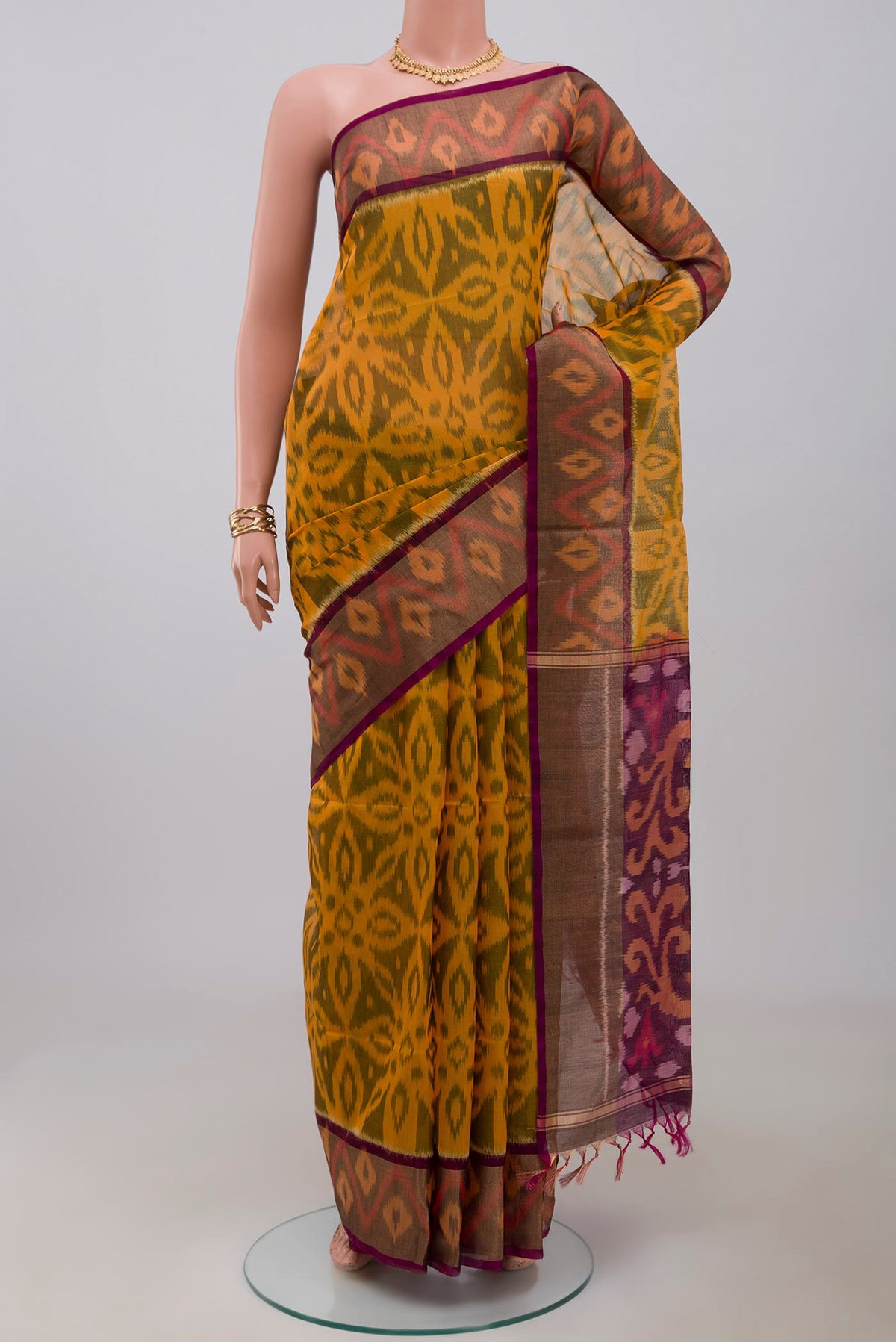 Yellow Silk Cotton Saree with Ikat Print on the body and Zari Border.  displayed on a mannequin