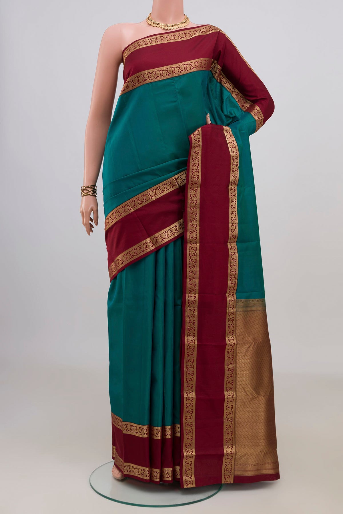 Pure Silk Green Kanchipuram Saree with Plain Body and Zari Border.  displayed on a mannequin