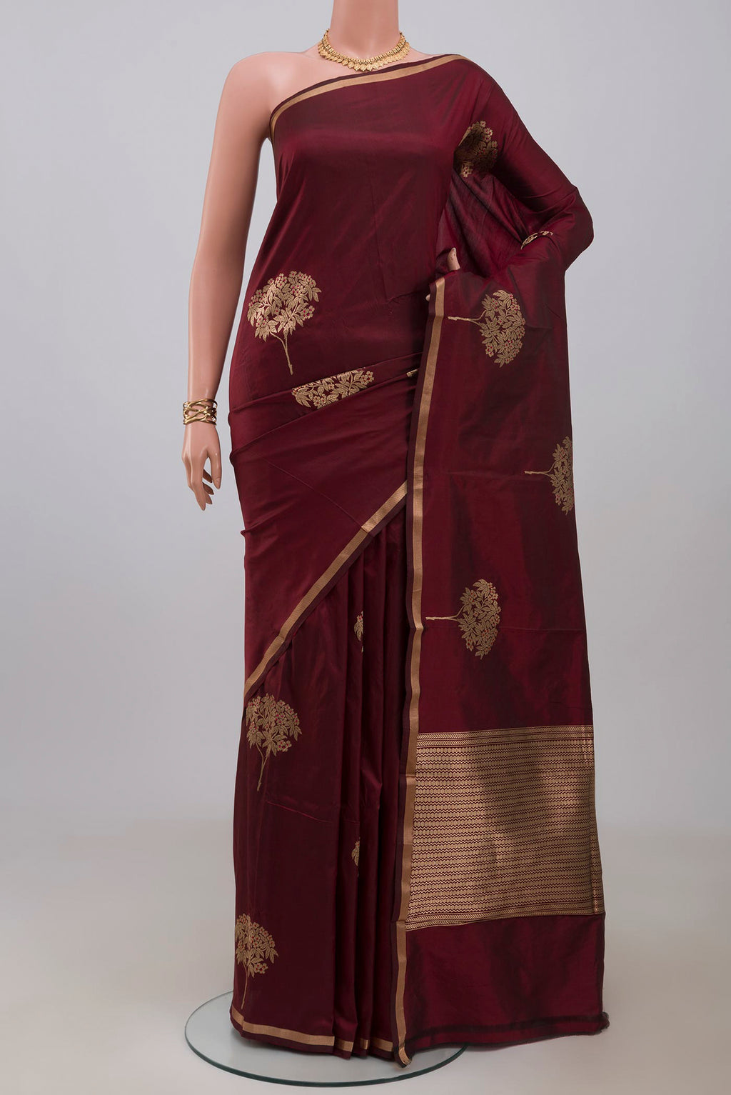 Maroon Banarasi Katan Silk Saree with Zari Butta on the body and Thin Zari Line.  displayed on a mannequin