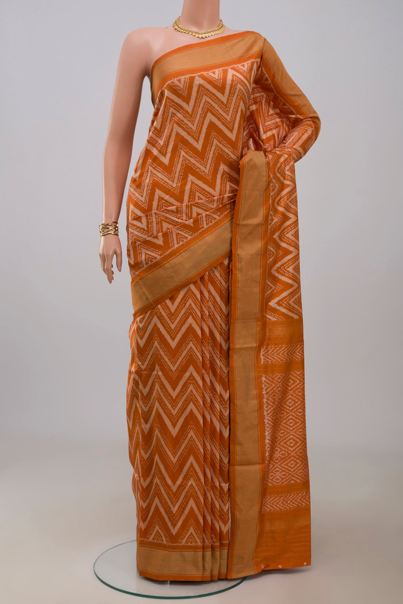 Rust Pochampally Saree with Ikat design on the body and Zari Border.  displayed on a mannequin