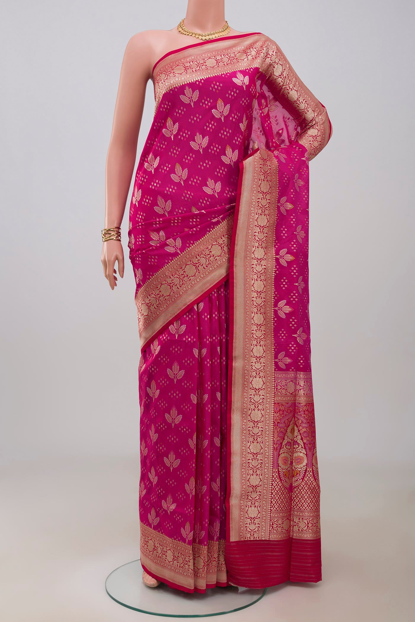 Rani Pink Banarasi Silk Saree with Zari And Thread Butta on the body and Fancy Border.  displayed on a mannequin