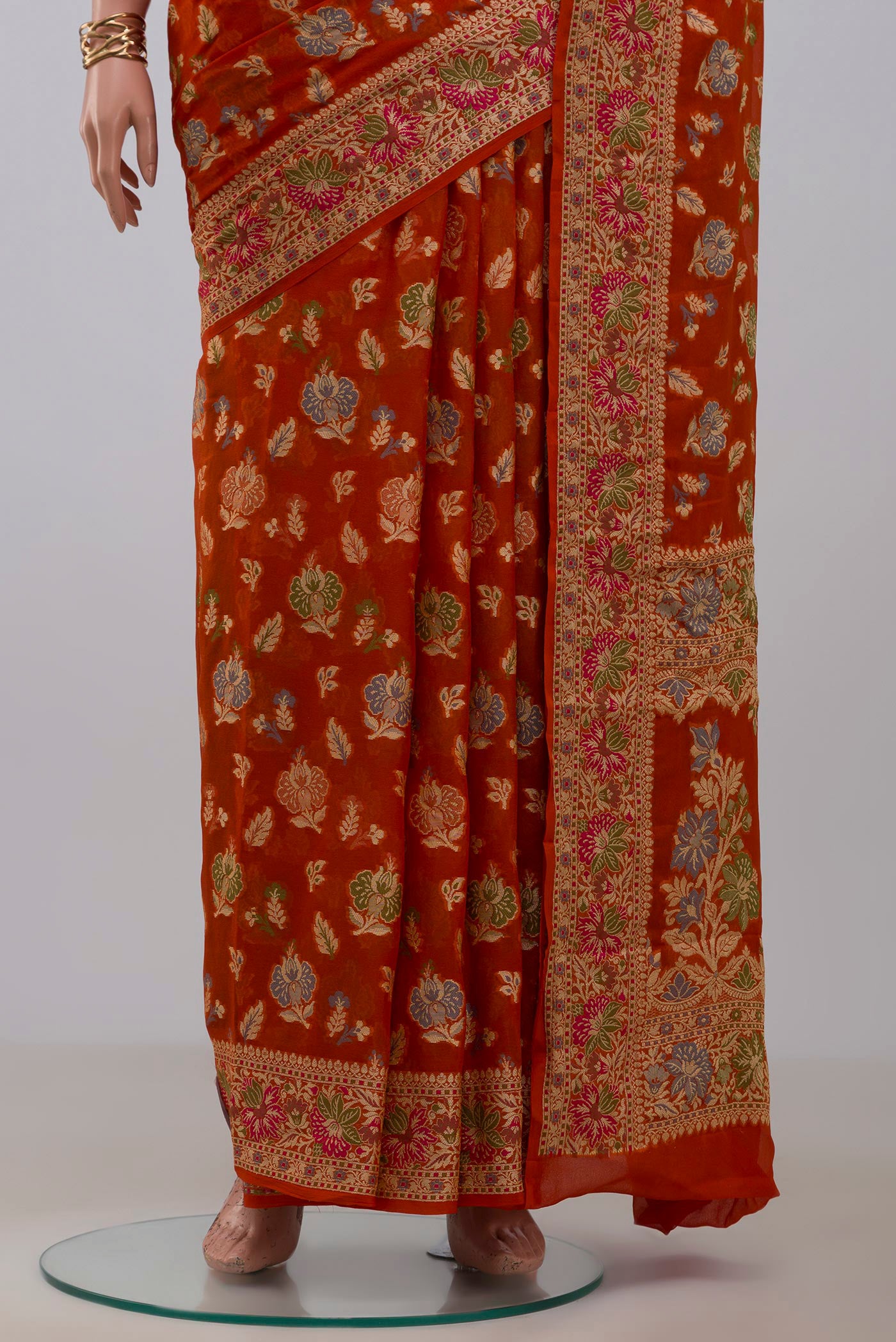 Pleats and pallu of Orange Banarasi Georgette Saree with Zari And Thread Butta on the body and Zari And Thread Border. 