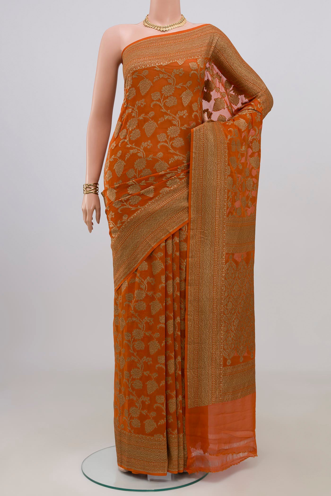 Brick Orange Banarasi Georgette Saree with Zari Brocade on the body and Zari Border.  displayed on a mannequin