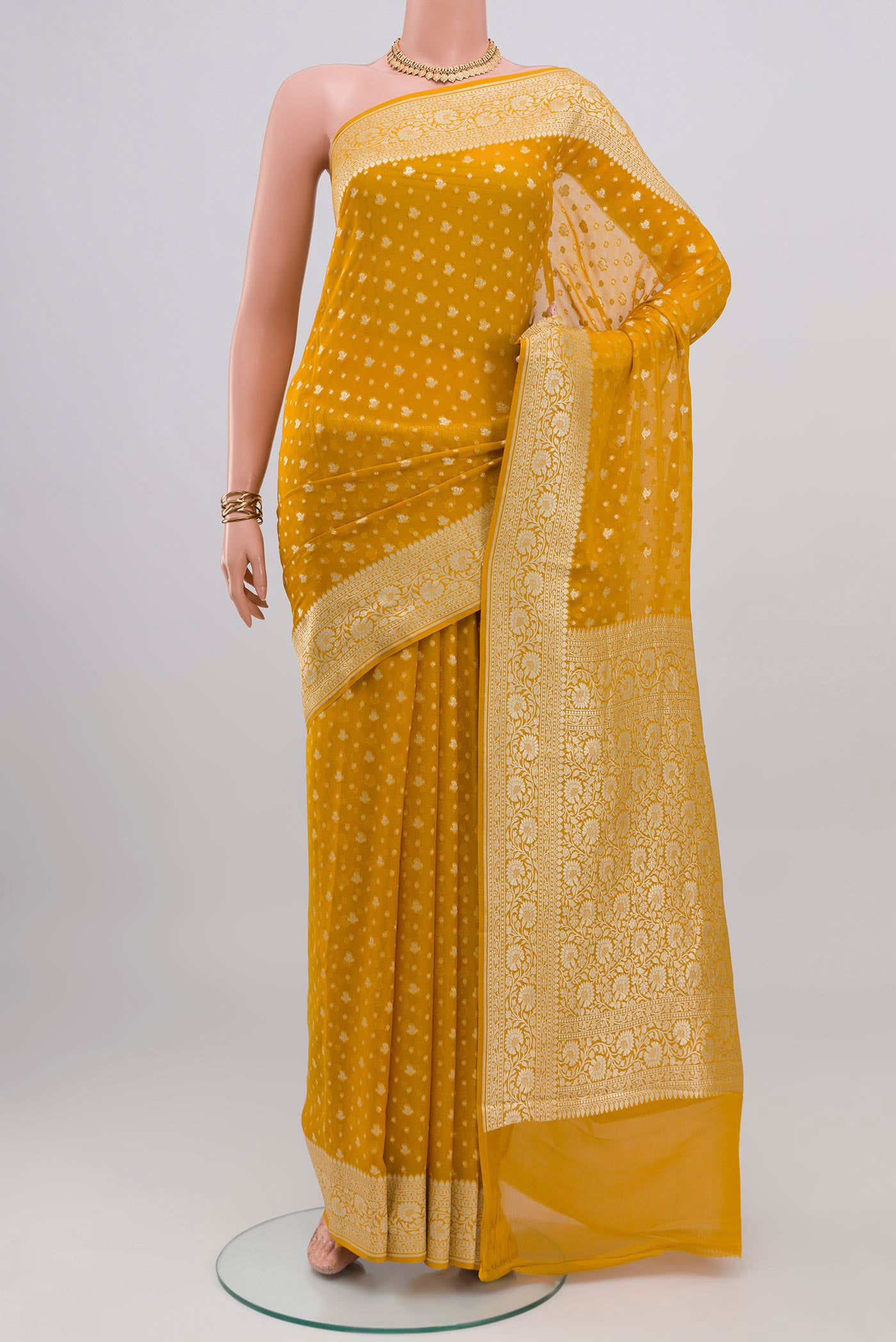 Mustard Banarasi Georgette Saree with Zari Butta on the body and Zari Border.  displayed on a mannequin