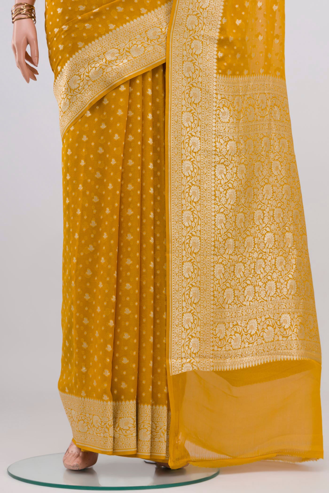 Pleats and pallu of Mustard Banarasi Georgette Saree with Zari Butta on the body and Zari Border. 