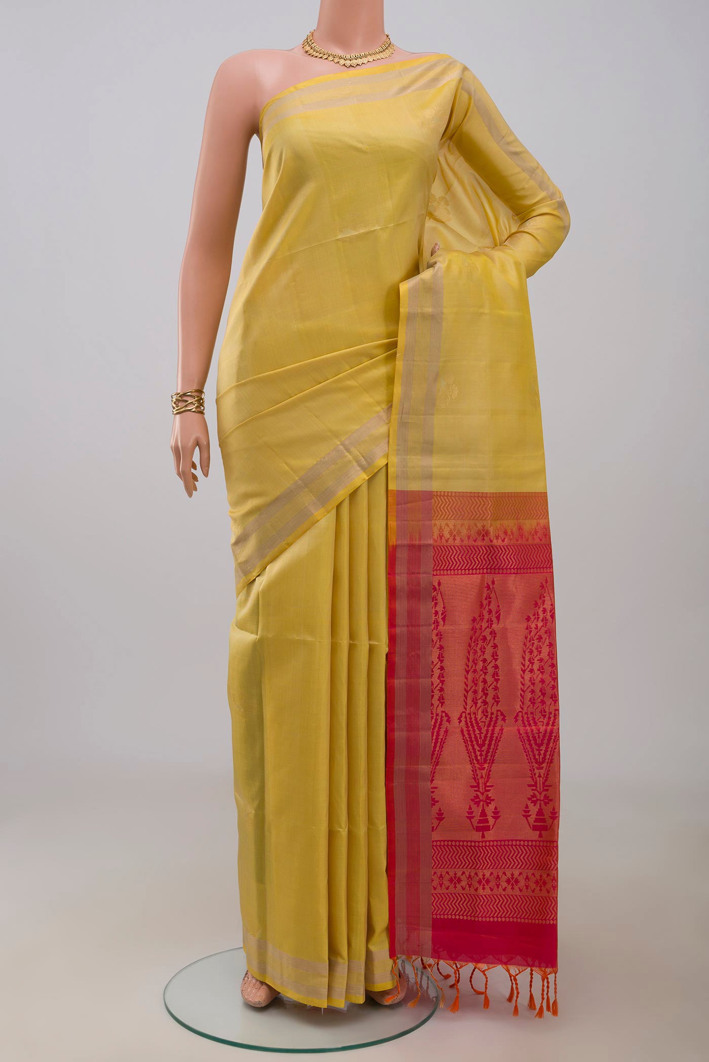 Yellow Soft Silk Saree with Zari Butta on the body and Zari Border.  displayed on a mannequin