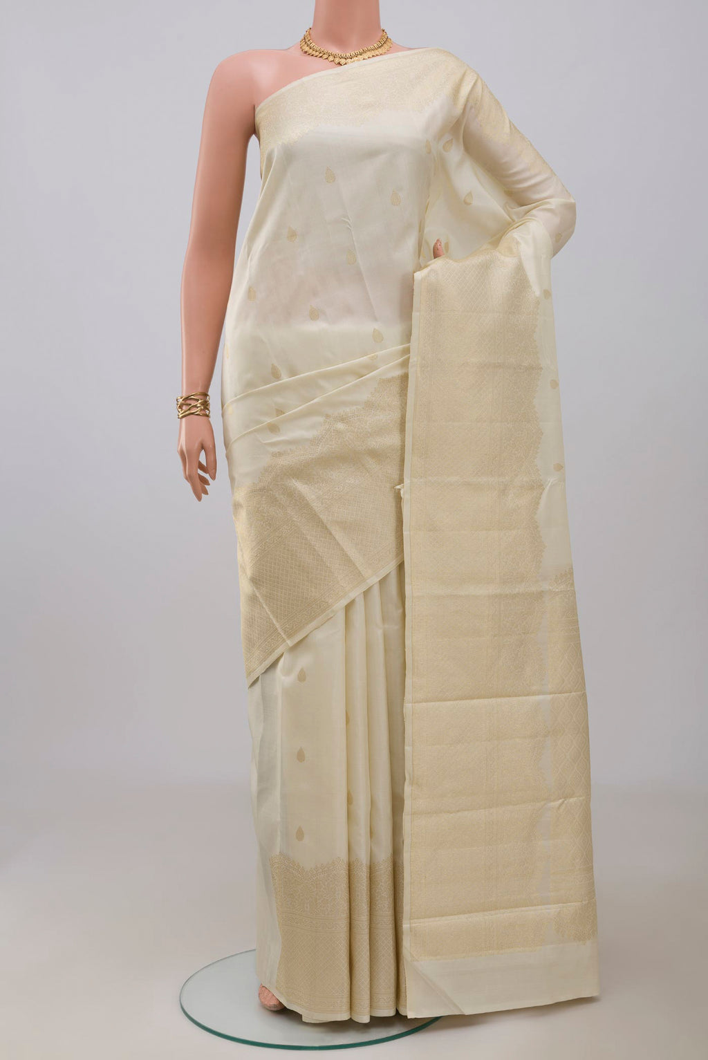 Off White Kanjivaram Silk Saree with Zari Butta on the body and Zari Border.  displayed on a mannequin