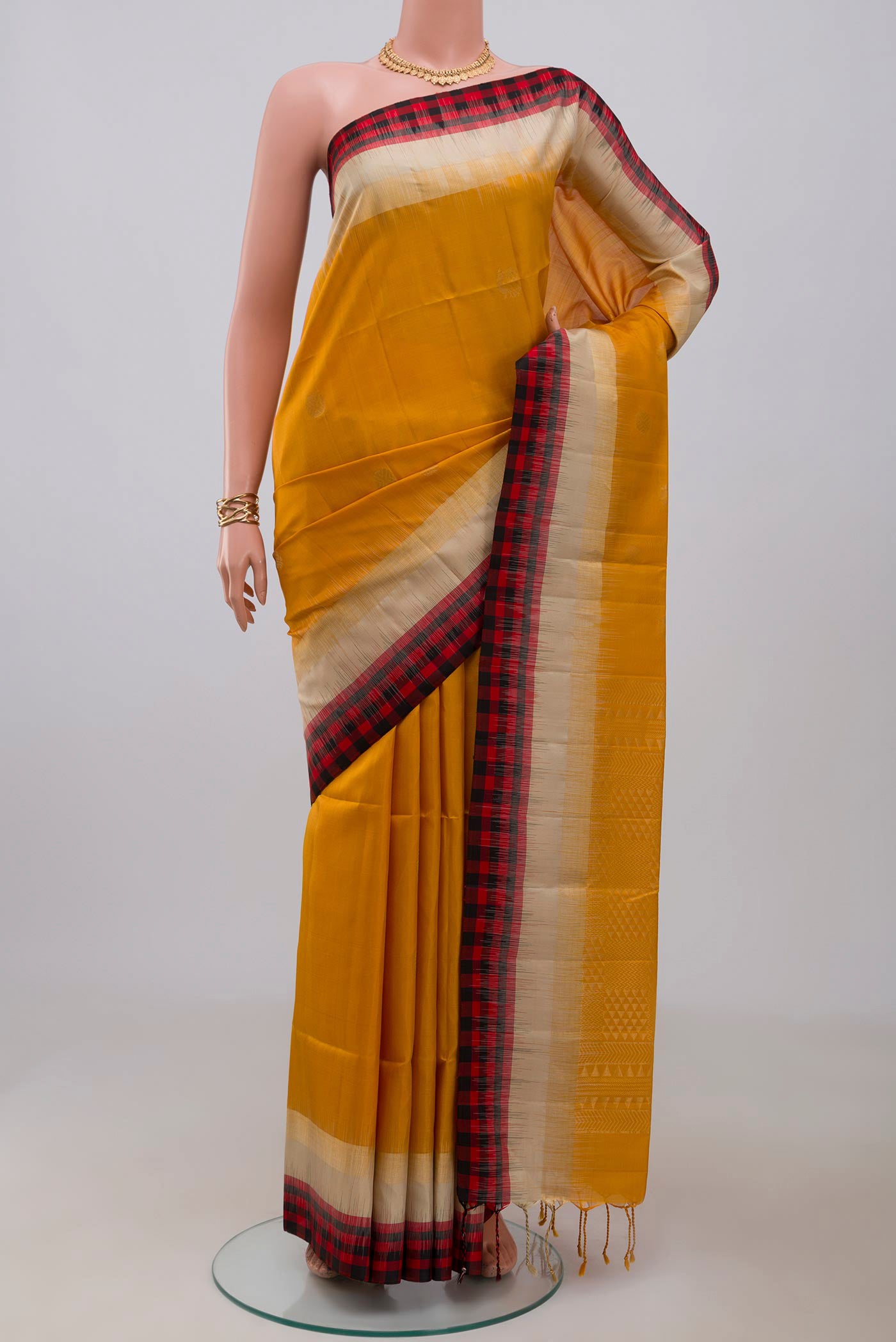 Yellow Soft Silk Saree with Zari Butta on the body and Fancy Border.  displayed on a mannequin