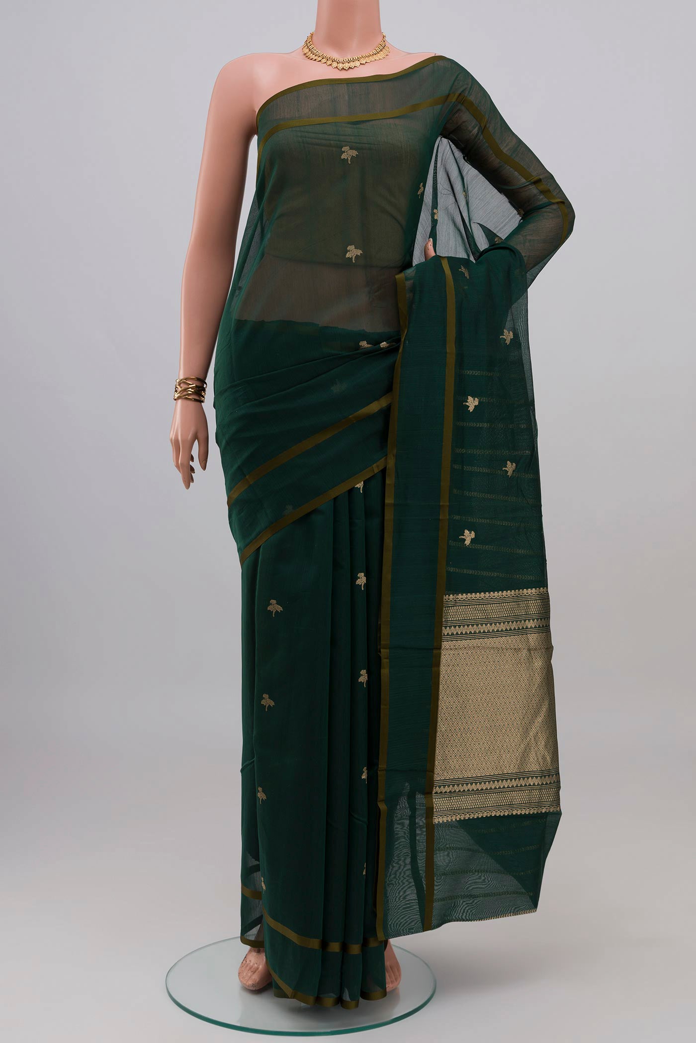 Bottle Green Kora Cotton Saree with Zari Butta on the body and Thin Zari Line.  displayed on a mannequin