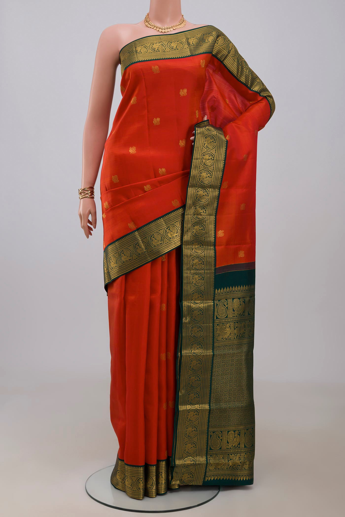 Orange Kanjivaram Silk Saree with Zari Butta on the body and Zari Border.  displayed on a mannequin