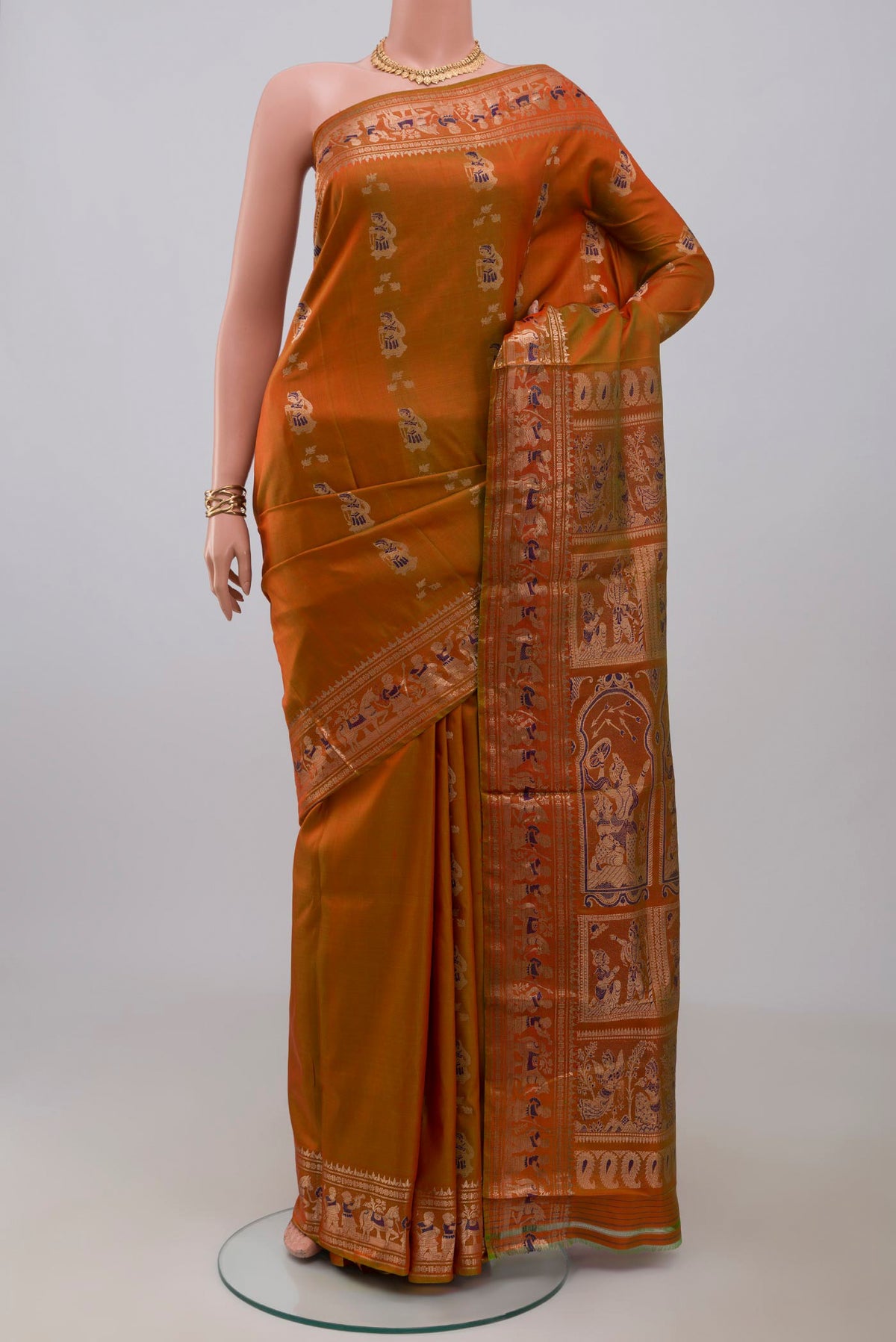 Brick Orange Baluchari Silk Saree with Zari And Thread Butta on the body and Zari Border.  displayed on a mannequin