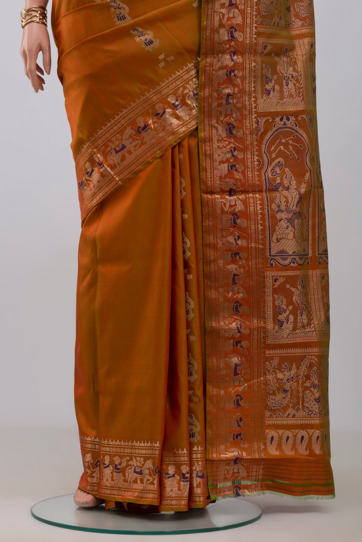 Pleats and pallu of Brick Orange Baluchari Silk Saree with Zari And Thread Butta on the body and Zari Border. 