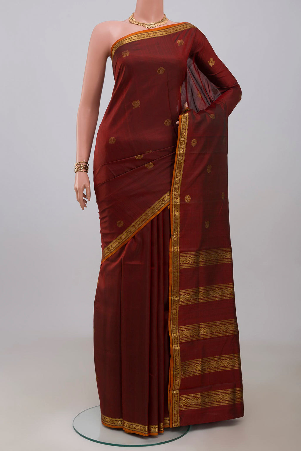 Maroon Kanchipuram Silk Saree with Zari Butta on the body and Zari Border.  displayed on a mannequin