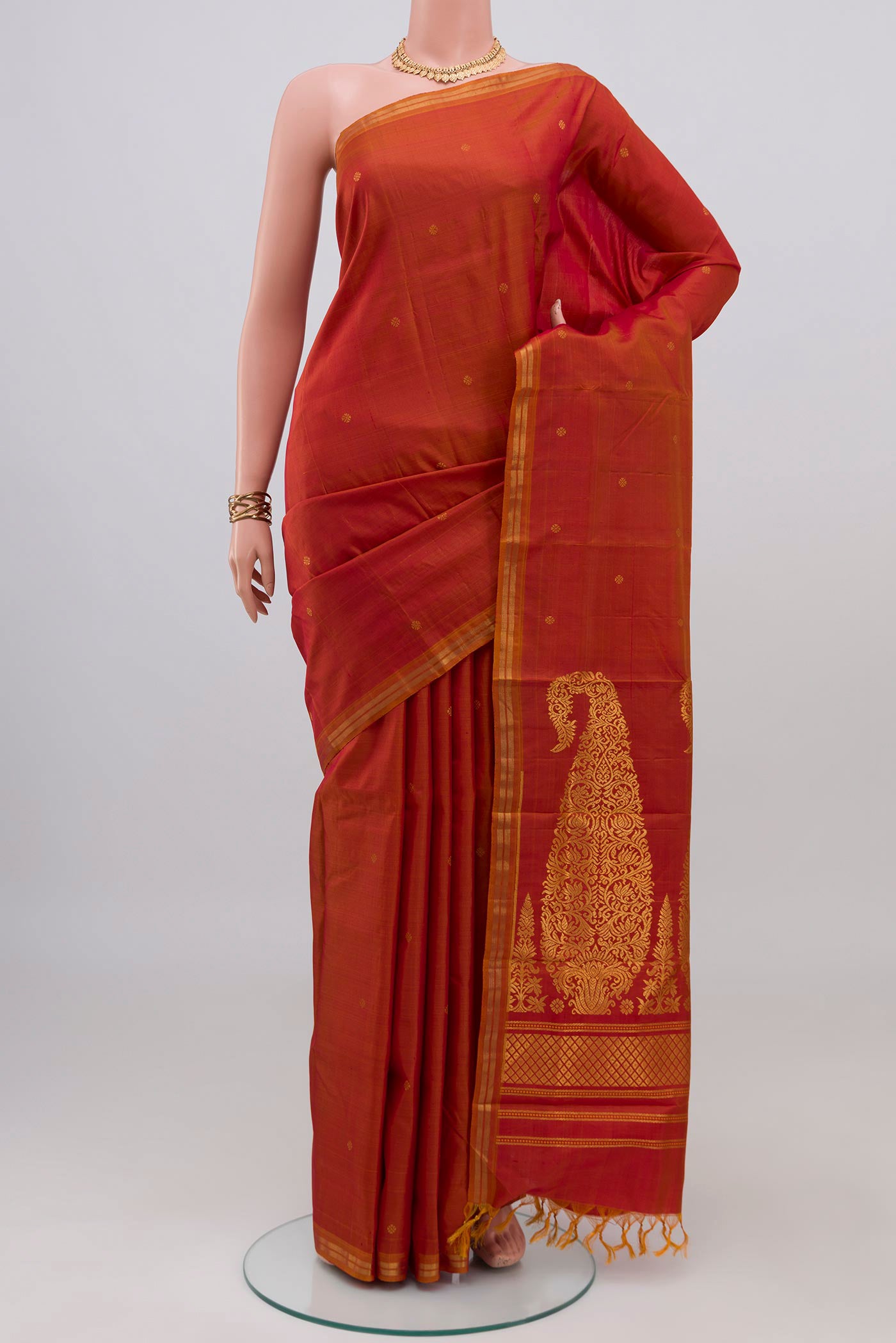 Brick Orange Dual Tone Kanchipuram Silk Saree with Zari Butta on the body and Thin Zari Line.  displayed on a mannequin