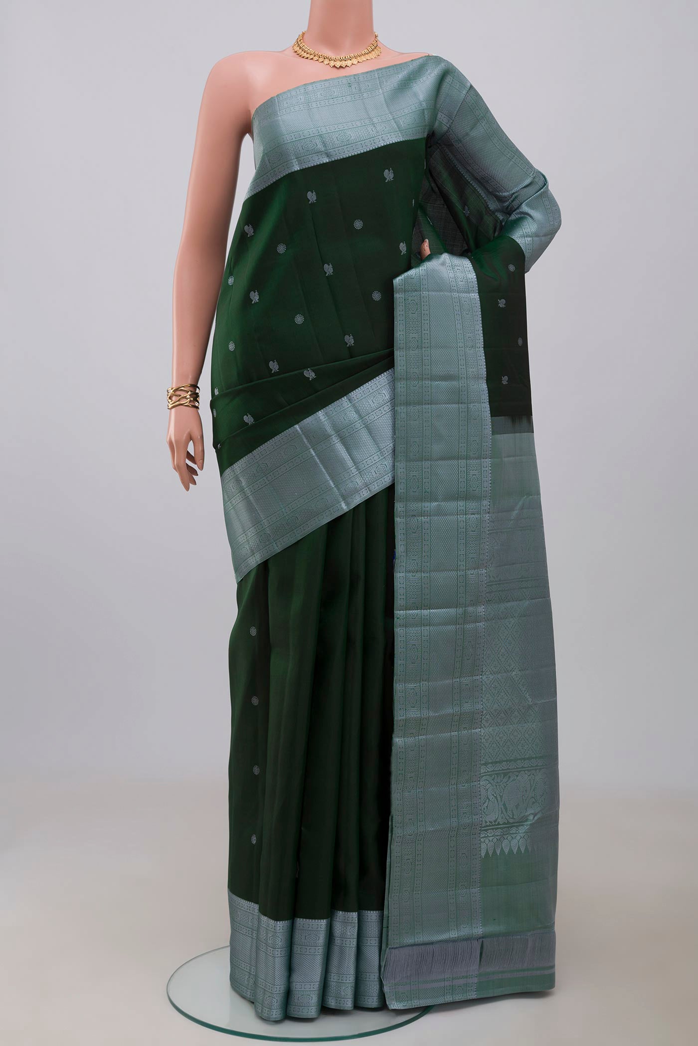 Bottle Green Kanchipuram Silk Saree with Thread Butta on the body and Thread Border.  displayed on a mannequin