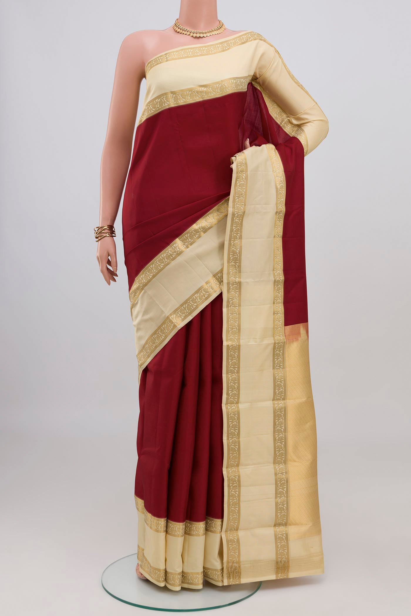 Maroon Kanchipuram Silk Saree with Plain Body and Zari Border.  displayed on a mannequin