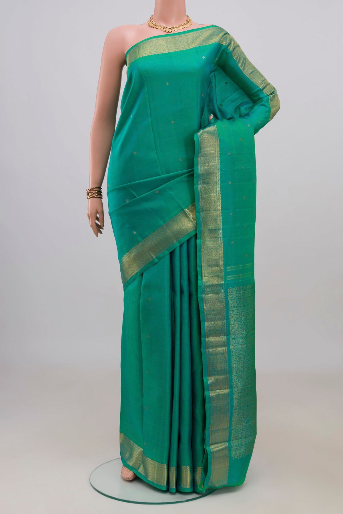 Pure Silk Sea Green Kanjivaram Saree with Zari Butta on the body and Zari Border.  displayed on a mannequin