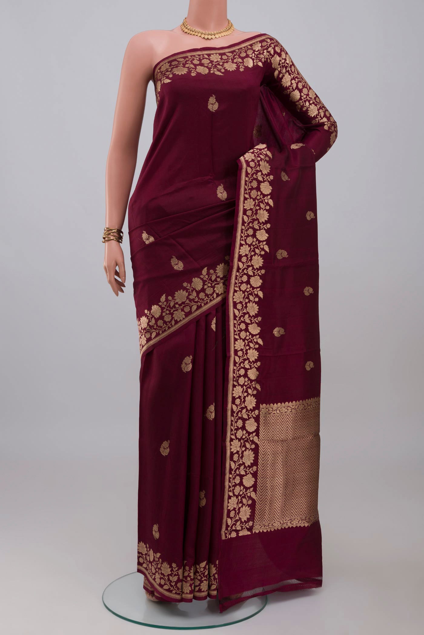 Maroon Banarasi Katan Silk Saree with Zari Butta on the body and Fancy Border.  displayed on a mannequin