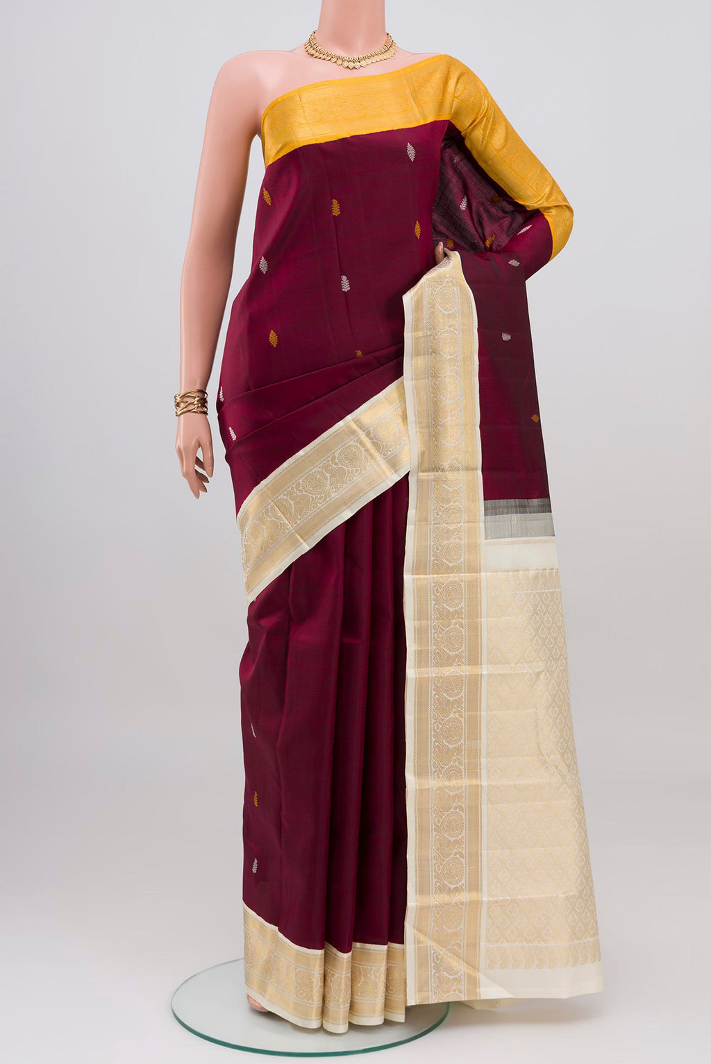 Maroon Kanjivaram Silk Saree with Thread Butta on the body and Ganga Jamuna Border.  displayed on a mannequin