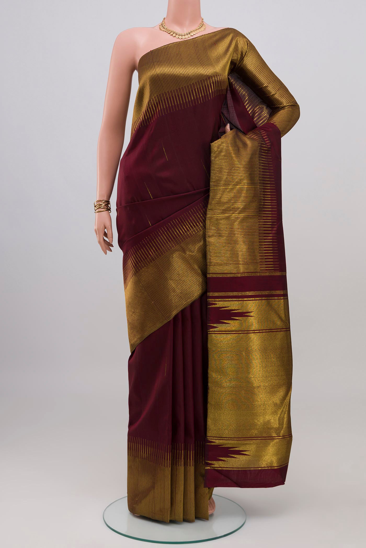 Maroon Kanjivaram Silk Saree with Zari Butta on the body and Fancy Border.  displayed on a mannequin