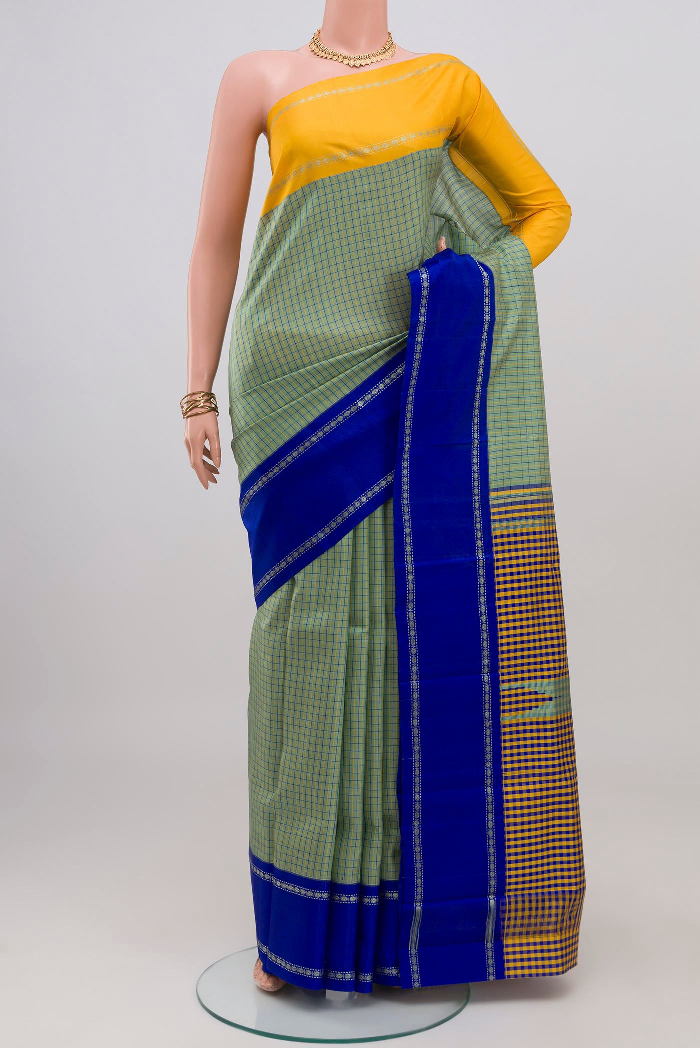 Green Kanchipuram Silk Saree with Checked design on the body and Ganga Jamuna Border.  displayed on a mannequin