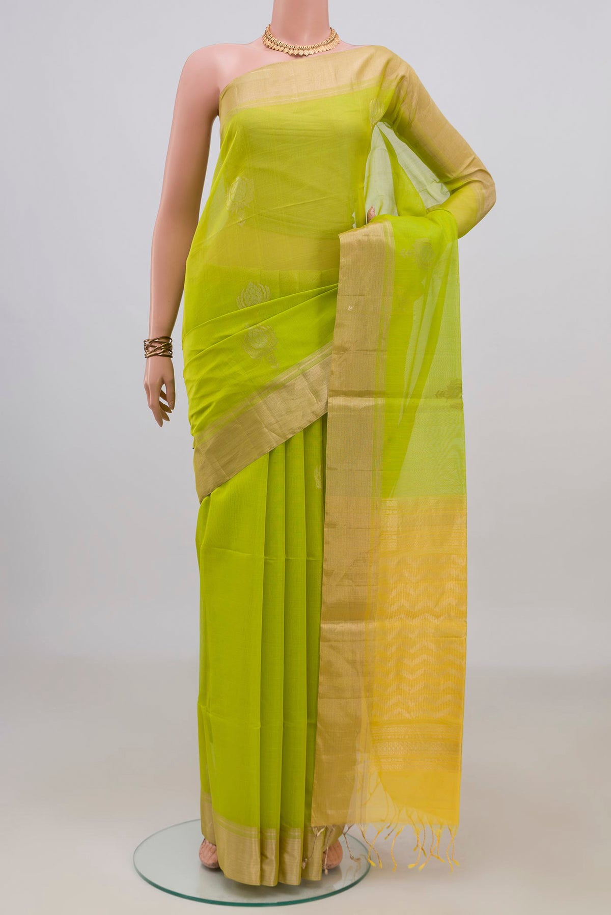 Parrot Green Silk Cotton Saree with Zari Butta on the body and Zari Border.  displayed on a mannequin