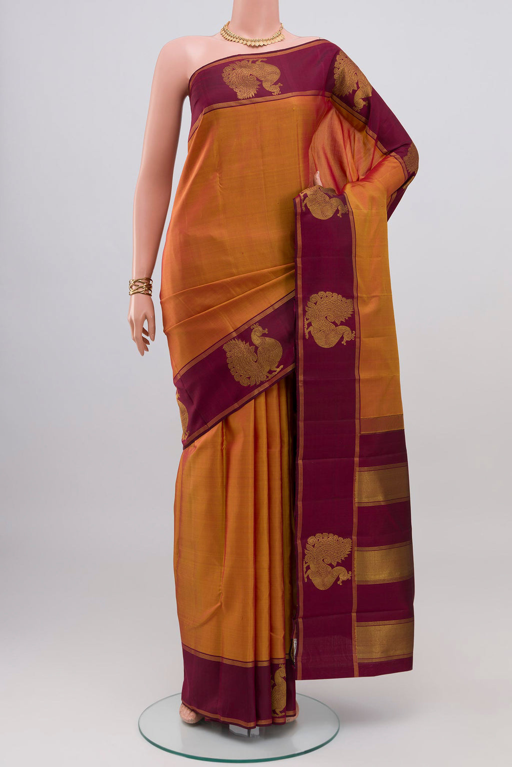 Mustard Kanchipuram Silk Saree with Plain Body and Fancy Border.  displayed on a mannequin