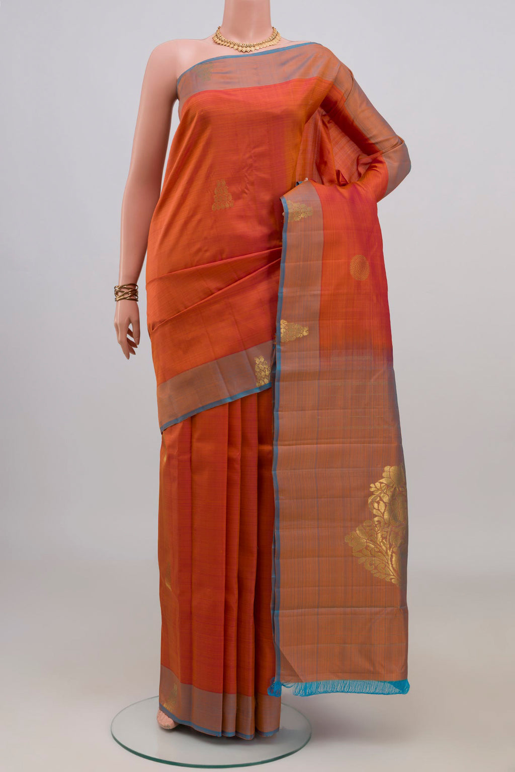 Pure Silk Orange Kanchipuram Saree with Zari Butta on the body and Fancy Border.  displayed on a mannequin
