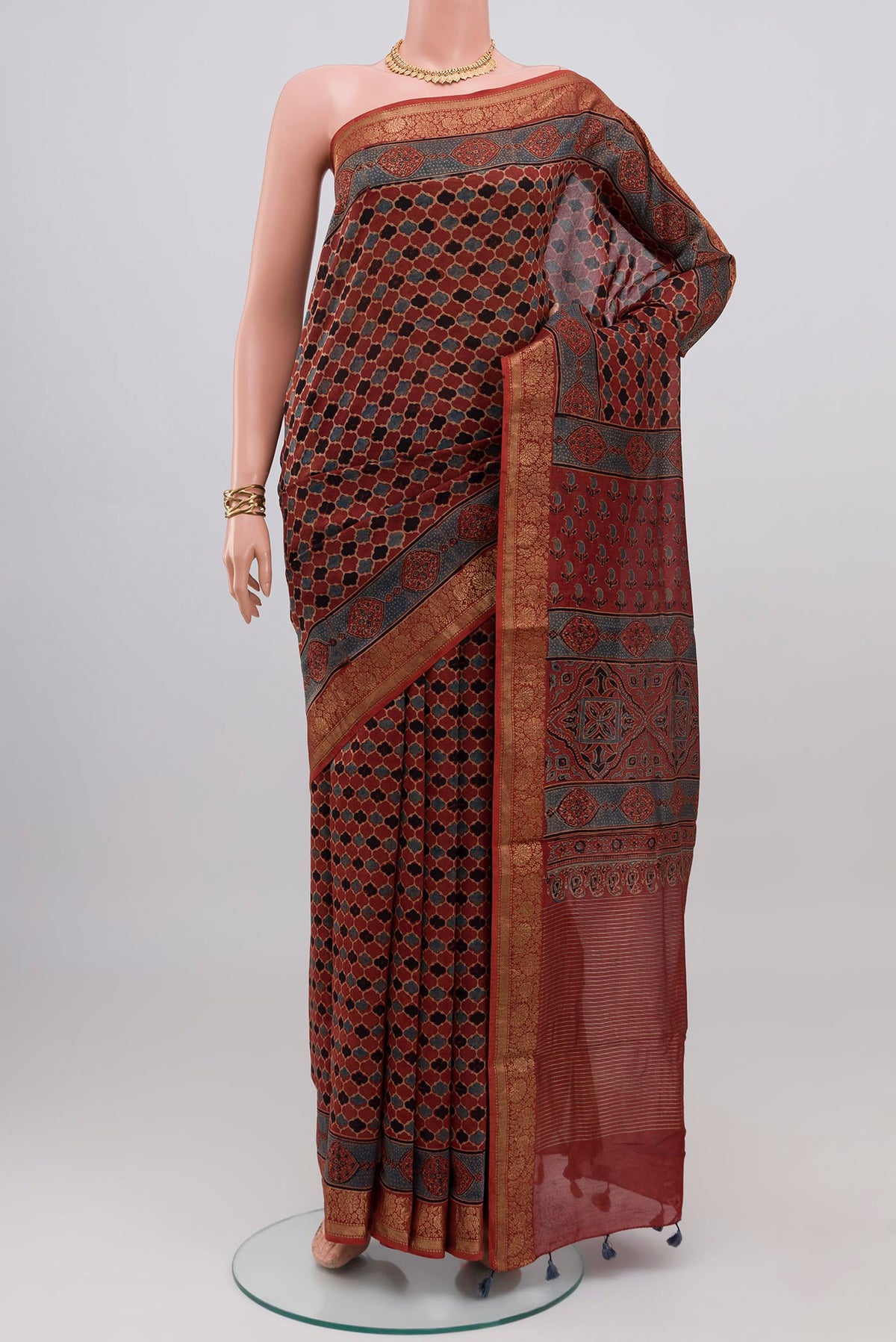 Rust Chanderi Silk Cotton Saree with Ajrakh Print on the body and Zari Border.  displayed on a mannequin