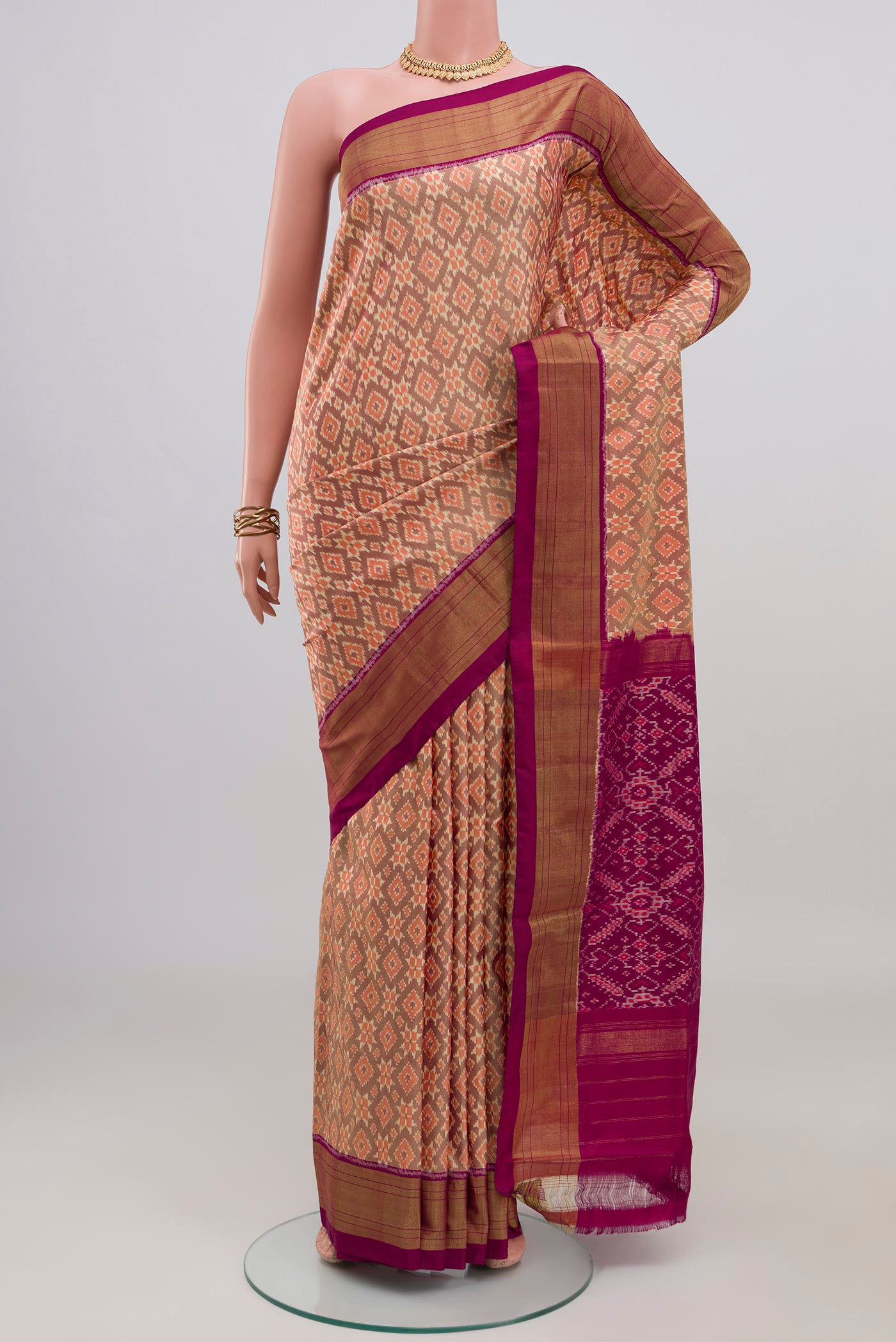 Peach Pochampally Silk Saree with Ikat design on the body and Zari Border.  displayed on a mannequin
