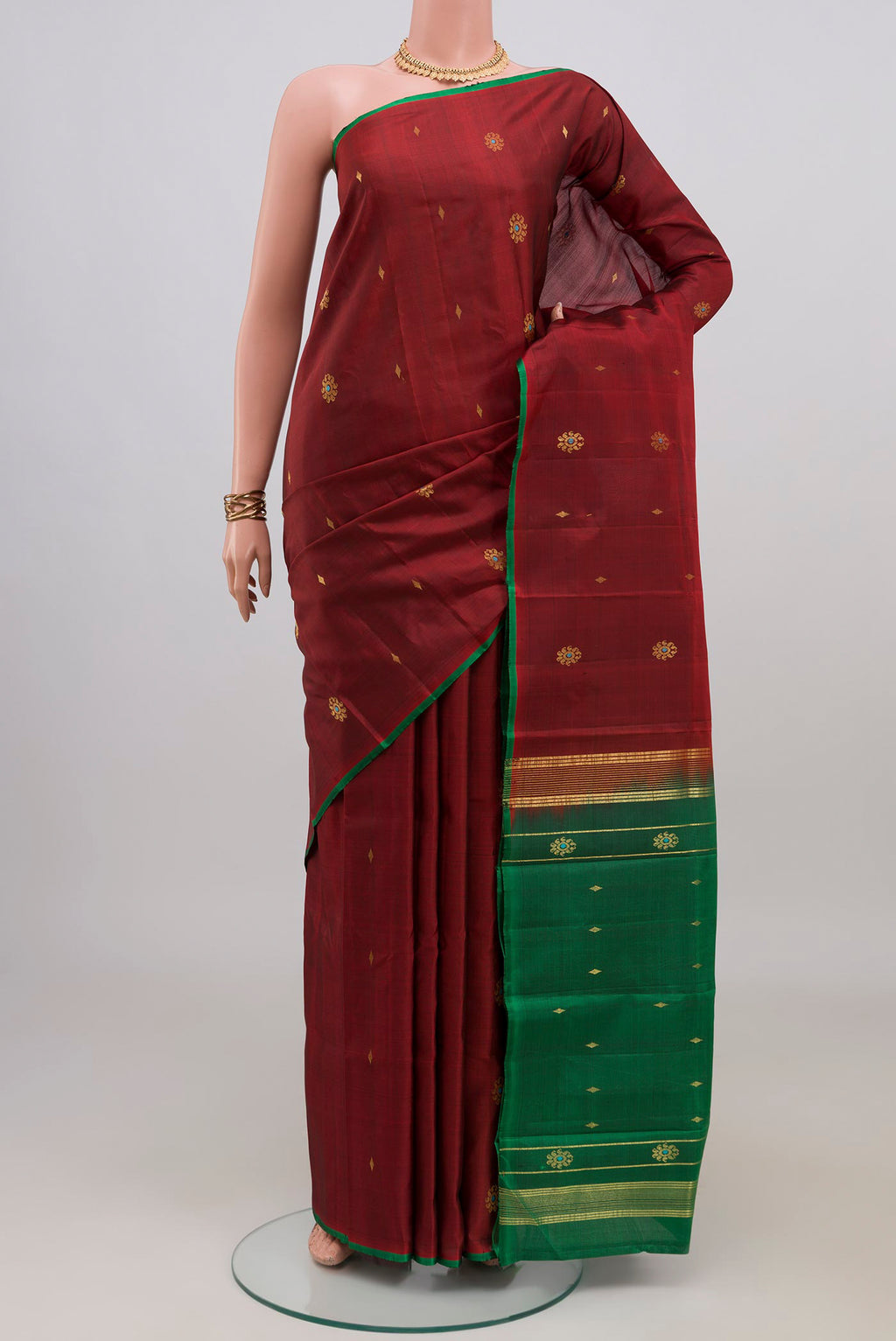Maroon Kanchipuram Silk Saree with Zari Butta on the body and Without Border.  displayed on a mannequin