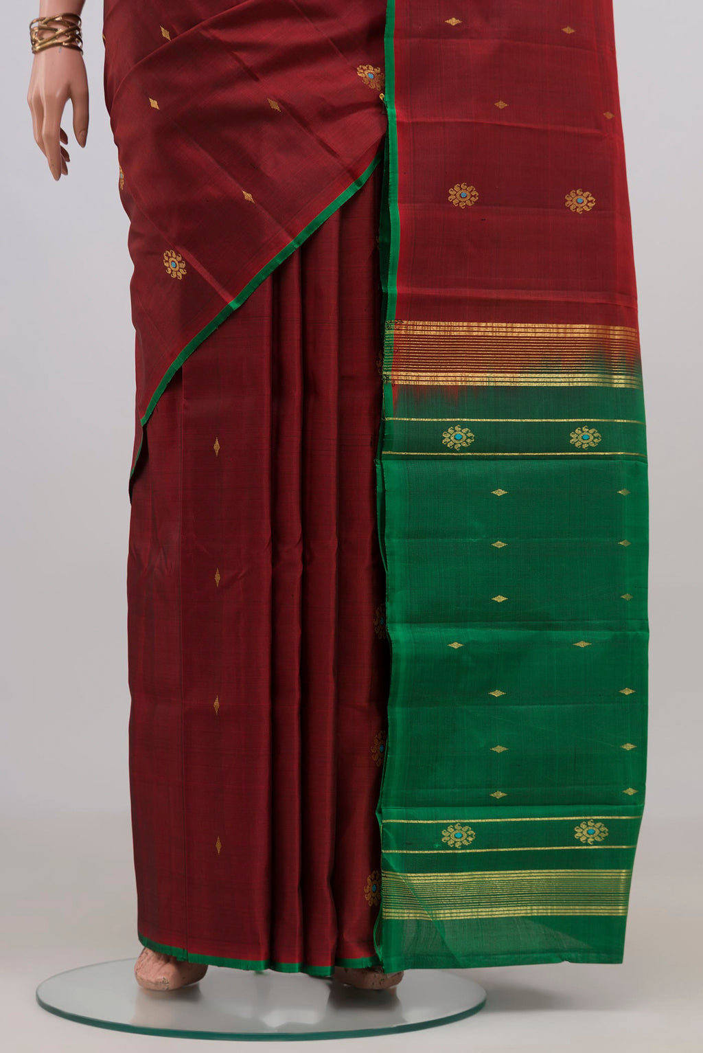Pleats and pallu of Maroon Kanchipuram Silk Saree with Zari Butta on the body and Without Border. 