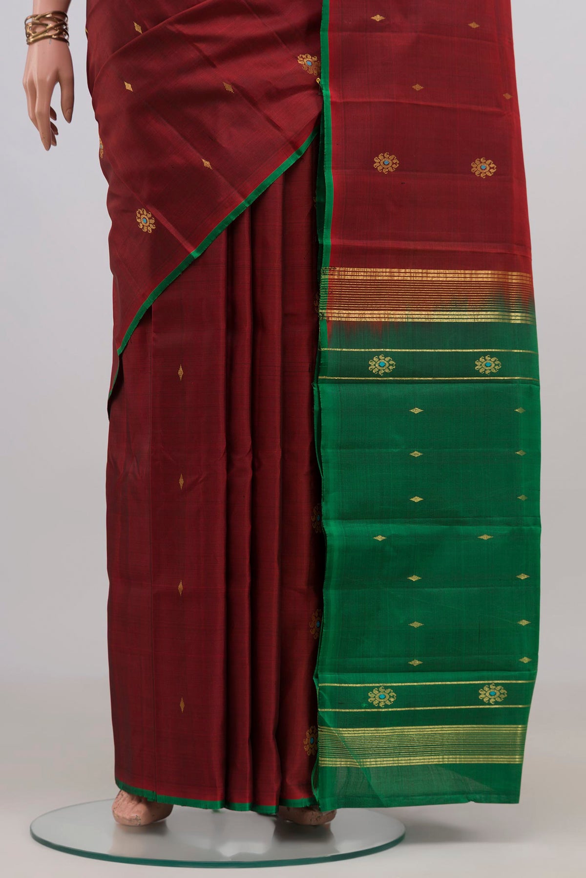 Pleats and pallu of Maroon Kanchipuram Silk Saree with Zari Butta on the body and Without Border. 