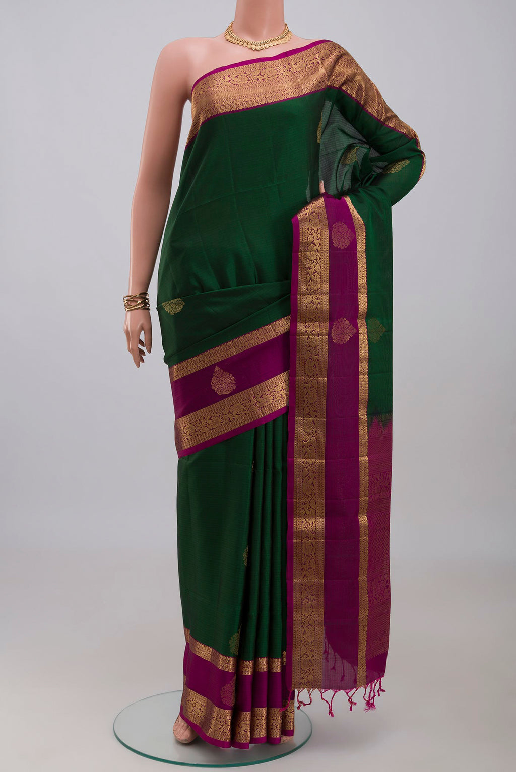 Bottle Green Soft Silk Saree with Zari Butta on the body and Zari Border.  displayed on a mannequin